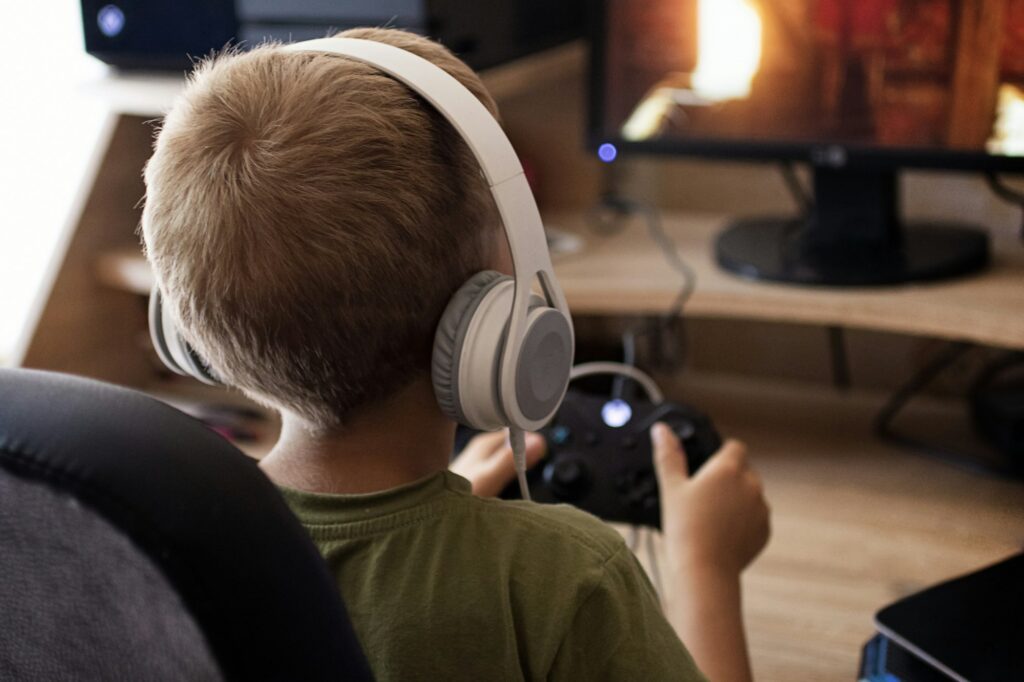 Child in headphones playing with joystick x-box.