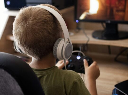 Child in headphones playing with joystick x-box.